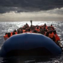 Rubber boat full of migrants after life jackets were distributed by the MOAS crew, before the process of transferring them to the rescue craft begins. 2016 was a deadly year of migrants and refugees trying to cross the mediterranean from Libya's coasts to Italy's. With ever increasing numbers of unseaworthy boats attempting the crossing, charities and NGOs like MOAS are often overwhelmed. MOAS, together with medicals teams from the red cross, operates two rescue vessels, the Responder and the Phoenix, just off the coast of Libya. They sit in international waters and await either the distress call from migrants lucky enough to have been given a satellite phone by their smuggler, or to visually find migrants boats - often in the dead of night. Then the race to rescue them before it too late starts.